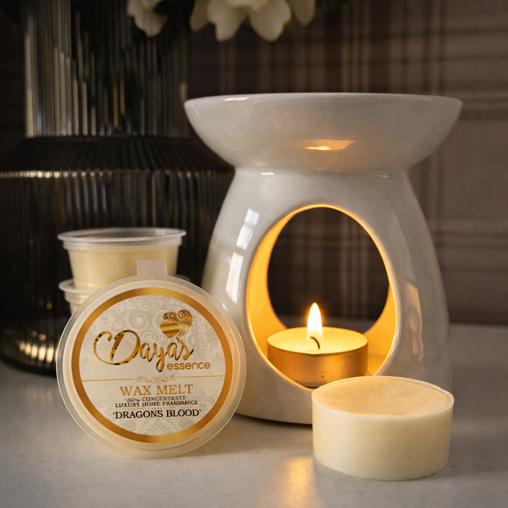 Dayas Essence Dragon’s Blood wax melt beside a white ceramic burner with a lit tealight, showing a single wax melt and packaging.