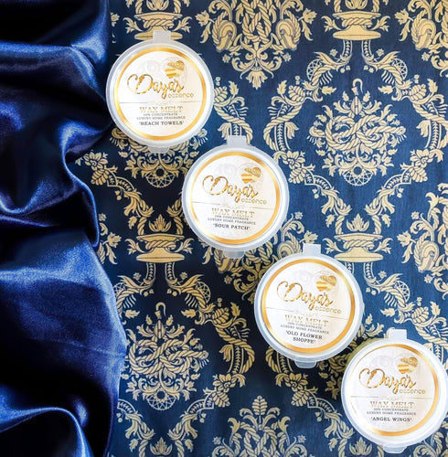 Four Daya's Essence wax melts on blue fabric with gold floral pattern, ideal gift option.